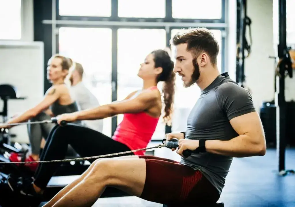 man and woman rowing in gym